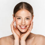 Choosing Between Surgical and Non-Surgical Facelift 1 beautiful woman smiling at camera and touching her face
