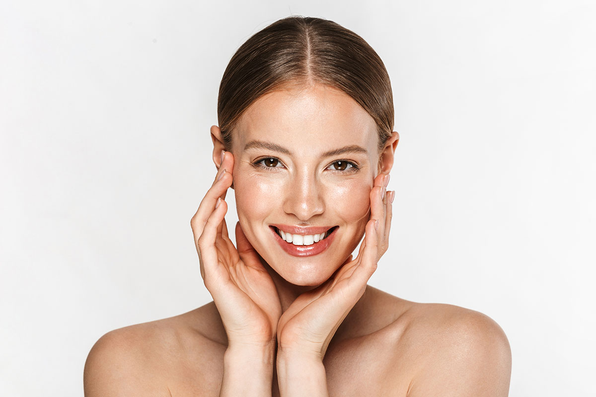 Choosing Between Surgical and Non-Surgical Facelift 1 beautiful woman smiling at camera and touching her face